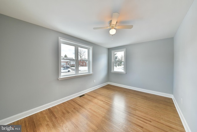 spare room featuring ceiling fan, light wood-type flooring, visible vents, and baseboards