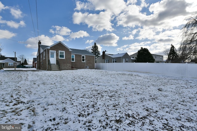 snowy yard featuring a residential view and fence