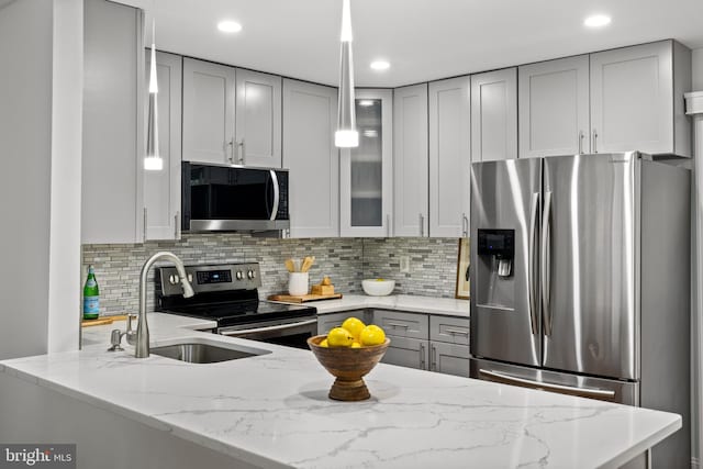 kitchen with light stone counters, gray cabinets, stainless steel appliances, glass insert cabinets, and backsplash