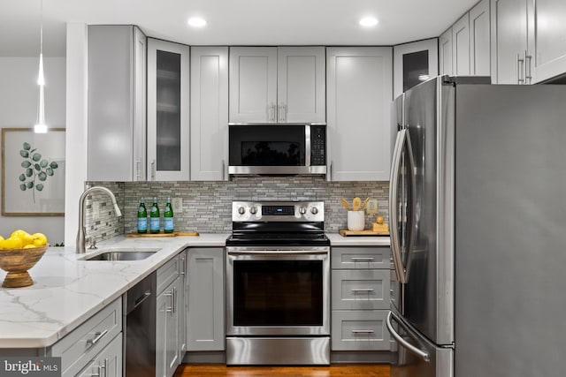 kitchen featuring a sink, light stone counters, gray cabinets, and stainless steel appliances