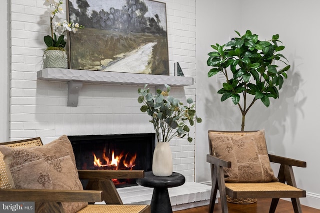 sitting room featuring a fireplace, baseboards, and wood finished floors