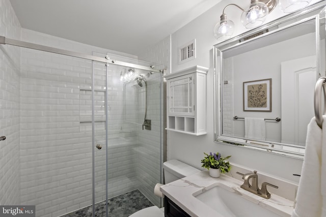 bathroom featuring vanity, toilet, visible vents, and a stall shower