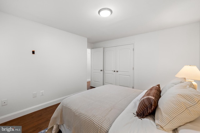 bedroom featuring dark wood-style floors, baseboards, and a closet