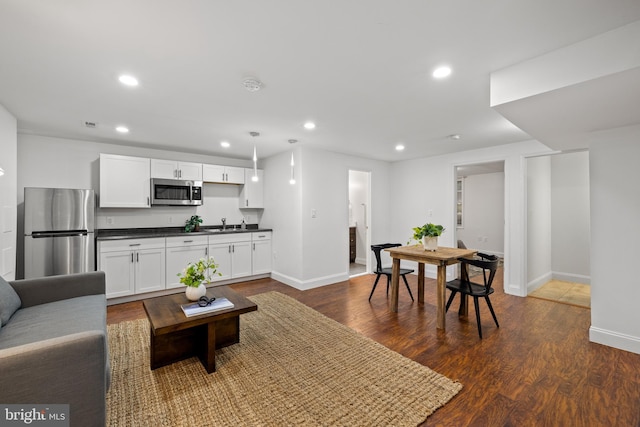 living area with recessed lighting, dark wood-type flooring, and baseboards