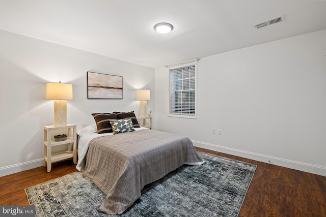 bedroom with visible vents, baseboards, and wood finished floors