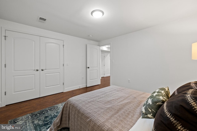 bedroom with a closet, visible vents, baseboards, and wood finished floors