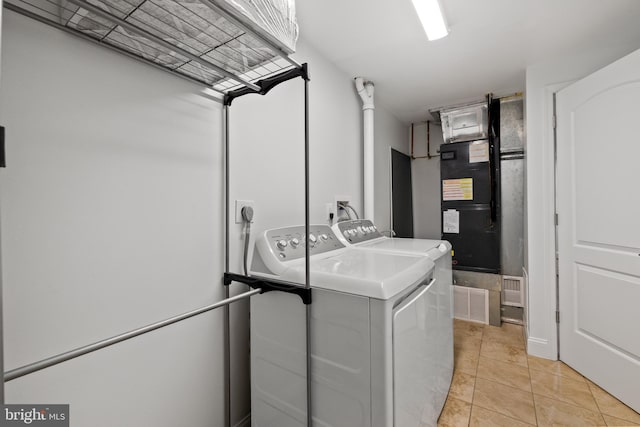 laundry area featuring heating unit, laundry area, light tile patterned floors, and independent washer and dryer