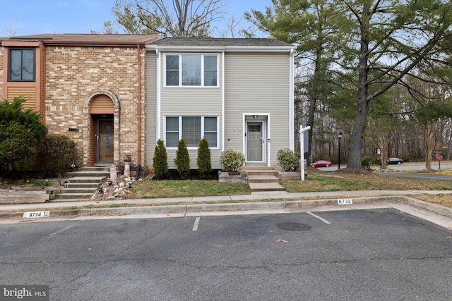 view of property with brick siding and uncovered parking