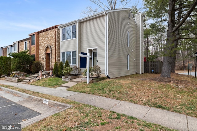 multi unit property featuring a front lawn, fence, and a chimney