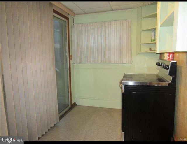 interior space featuring a paneled ceiling, electric stove, stainless steel countertops, and open shelves