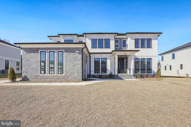 view of front of property featuring stone siding, central air condition unit, and stucco siding