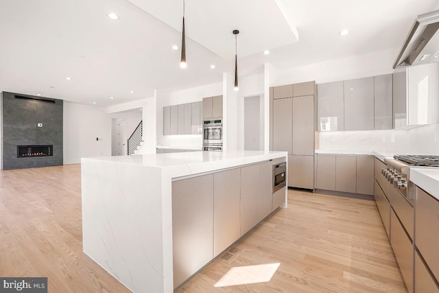 kitchen with light wood finished floors, a large island, modern cabinets, range hood, and gray cabinets