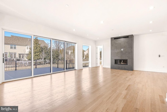 unfurnished living room featuring light wood-type flooring, recessed lighting, baseboards, and a tile fireplace