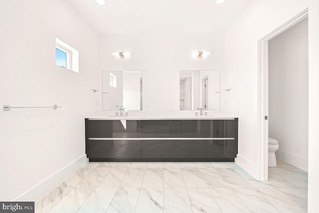 bathroom with marble finish floor, baseboards, toilet, and double vanity