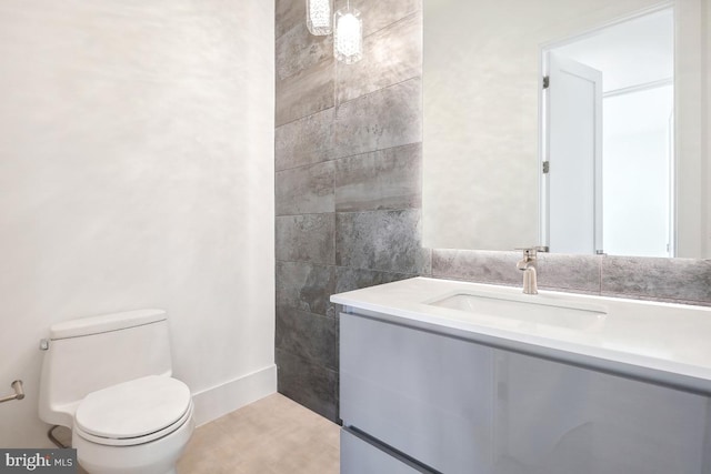 bathroom featuring toilet, vanity, and tile walls