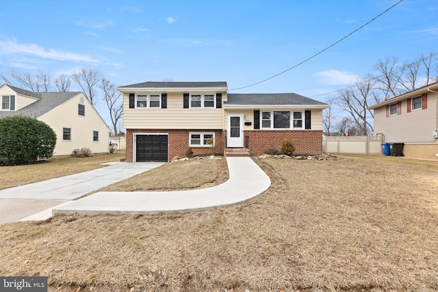 tri-level home with brick siding, driveway, a front lawn, and fence