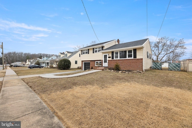 split level home featuring concrete driveway, a chimney, an attached garage, fence, and brick siding