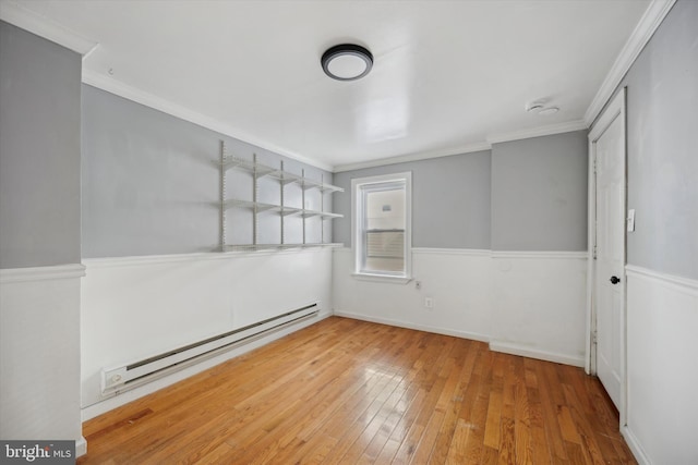 empty room with ornamental molding, a baseboard radiator, and wood finished floors