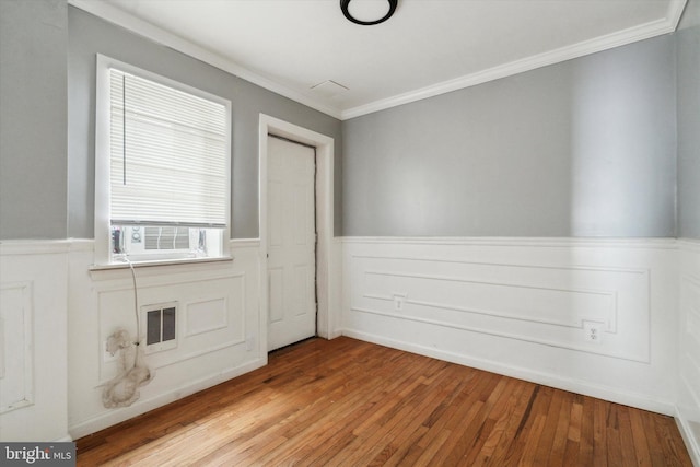 unfurnished room with a wainscoted wall, light wood-style flooring, visible vents, and cooling unit