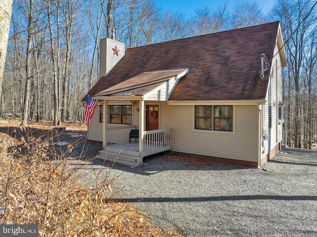 view of front of house with roof with shingles and a chimney