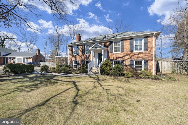 split foyer home with brick siding, a front lawn, a chimney, and fence