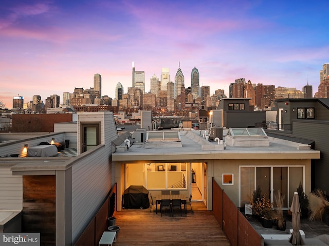 exterior space featuring a deck, outdoor dining area, and a city view