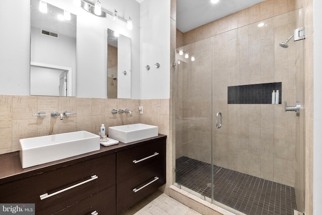 full bathroom featuring a stall shower, a sink, and visible vents