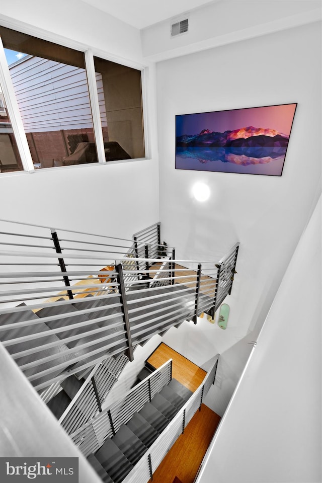 stairs with wood finished floors and visible vents