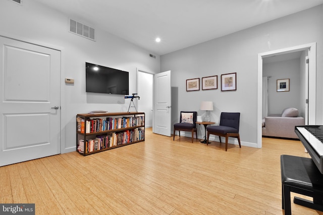 living area with baseboards, visible vents, and hardwood / wood-style floors