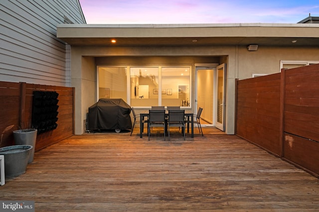 wooden deck featuring outdoor dining space, fence, and area for grilling