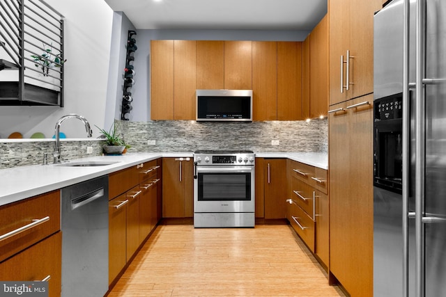 kitchen with stainless steel appliances, brown cabinets, a sink, and decorative backsplash