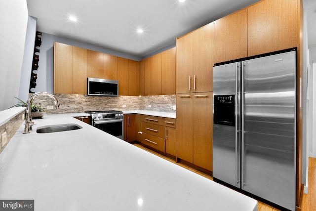 kitchen featuring appliances with stainless steel finishes, light countertops, a sink, and backsplash