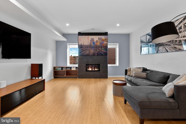 living room with recessed lighting, baseboards, a tiled fireplace, and hardwood / wood-style flooring