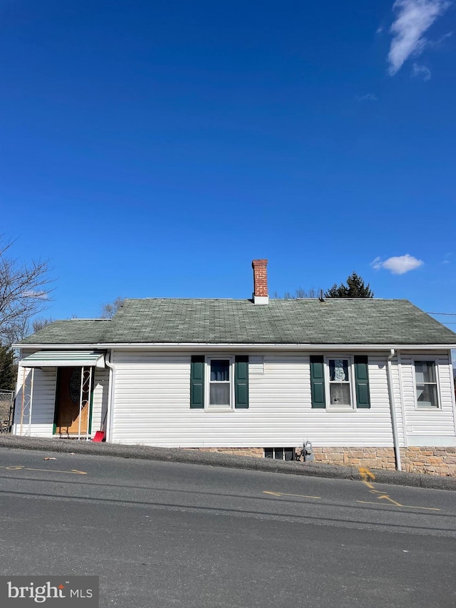 view of front of house featuring roof with shingles and a chimney