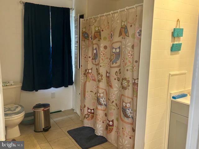 full bath with toilet, tile patterned floors, and curtained shower