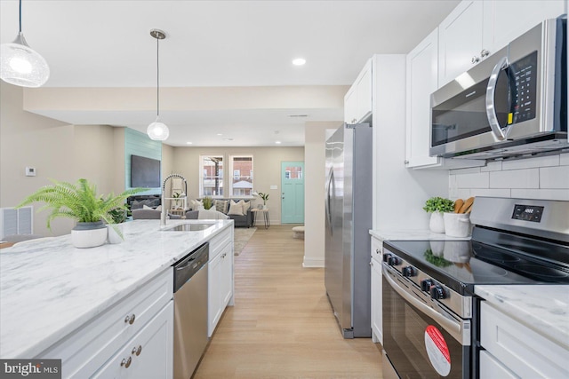 kitchen with visible vents, a sink, stainless steel appliances, white cabinetry, and open floor plan