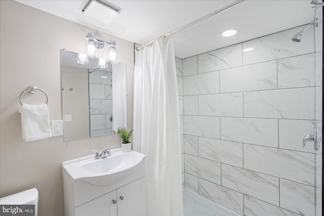 bathroom with toilet, vanity, and a tile shower