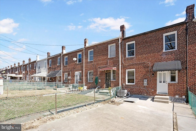 back of property with entry steps, cooling unit, fence, and brick siding