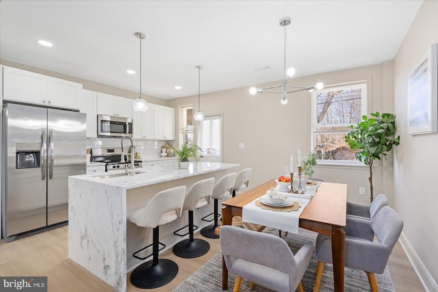 kitchen featuring light wood finished floors, backsplash, stainless steel appliances, and a sink