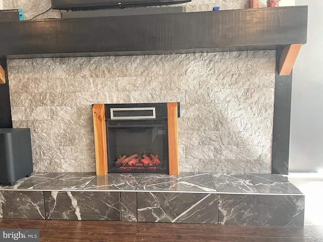 interior details featuring wood finished floors and a tiled fireplace