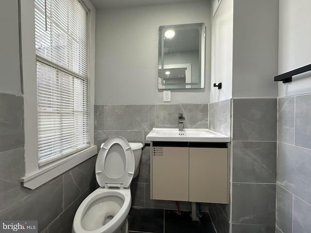 bathroom featuring tile walls, wainscoting, vanity, and toilet