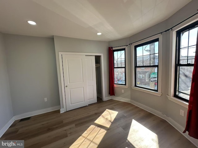 unfurnished bedroom featuring dark wood-style floors, multiple windows, and baseboards