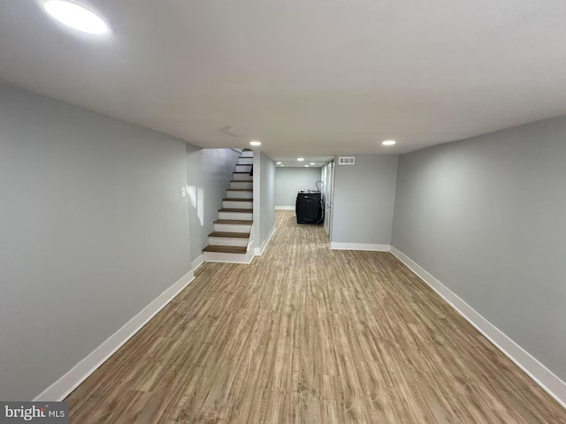 finished basement featuring light wood-type flooring, visible vents, stairway, and baseboards