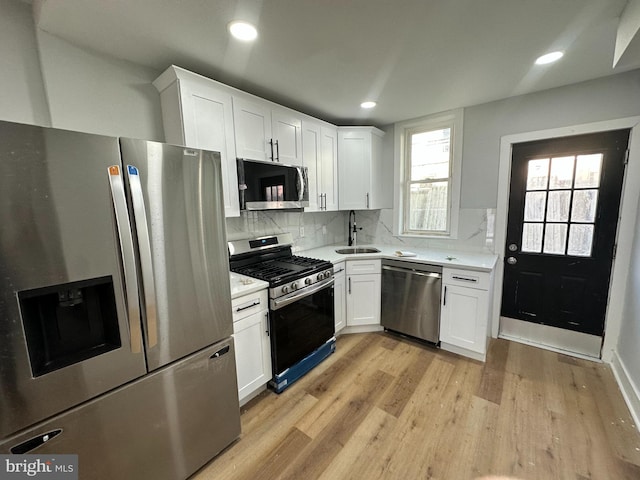 kitchen featuring light wood finished floors, light countertops, appliances with stainless steel finishes, white cabinetry, and a sink