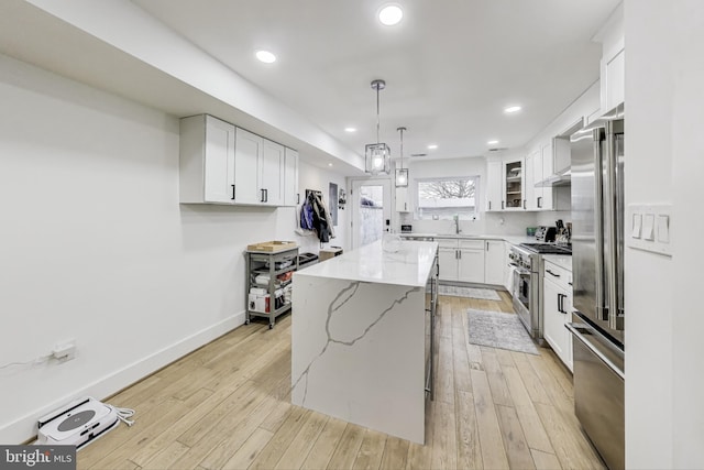 kitchen featuring glass insert cabinets, high quality appliances, white cabinetry, and a center island