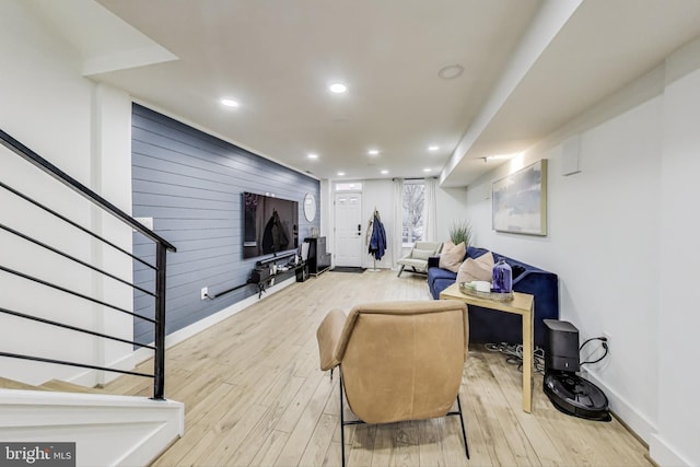 living room with stairs, wood walls, recessed lighting, and light wood-style floors