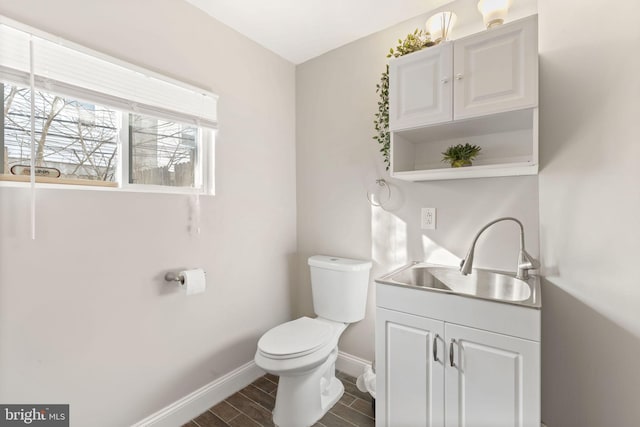 bathroom featuring wood finish floors, baseboards, vanity, and toilet