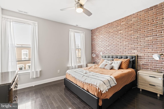 bedroom featuring brick wall, visible vents, baseboards, and dark wood-style flooring