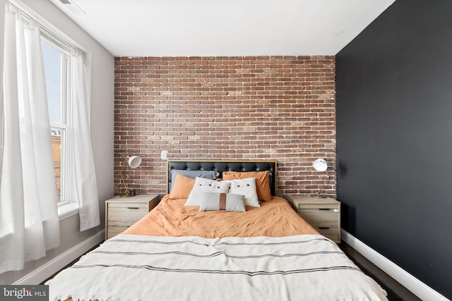 bedroom with brick wall, visible vents, and baseboards