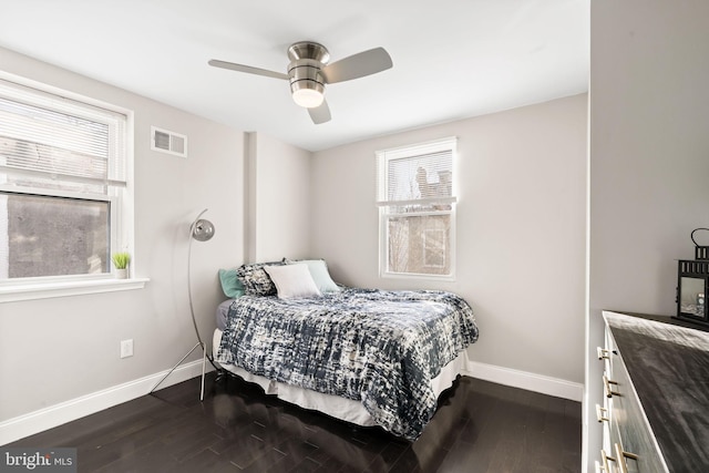 bedroom featuring dark wood-style floors, ceiling fan, visible vents, and baseboards